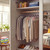 Open wardrobe with neutral clothes on hangers and shoes on lower shelf
