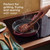 Red cast iron skillet grilling steak on hob, promoting easy grilling, frying or searing