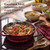 Red cast iron skillet with chicken and vegetables on hob, showing heat retention for even cooking