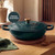 Green cast iron casserole dish with lid, wooden knob, on worktop, Lifetime Guarantee badge