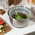 Silver salad spinner with clear lid and black handle, shown open