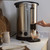 Salter stainless steel hot water urn with hand dispensing water into a glass cup