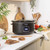 Black slow cooker with spiced winter punch, garnished with orange slices and cranberries