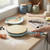 Electric crepe maker in pastel blue with batter on hot plate for making pancakes.