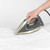 Steam iron in use on light pink shirt, showing steam function