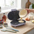 Purple waffle maker open with batter being poured in, on kitchen counter with ingredients