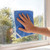 Hand cleaning window with blue microfiber cloth
