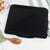 Black non-stick oven tray, photographed top down with logo on handle