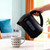 Black electric kettle pouring hot water into patterned mug on kitchen table