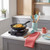 Black electric hot plate with frying pan cooking noodles in modern kitchen setting