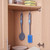 Two grey and blue dish brushes hanging on a cupboard rail