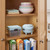 Light blue mini waffle maker on kitchen shelf beside cutlery box