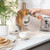 Beige ribbed electric kettle pouring hot water into cup, kitchen counter setting