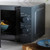 Grey microwave oven with mechanical dials shown heating food, door open