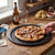 Hand taking slice of chicken and onion pizza on tray in kitchen setting