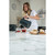 Grey electric kettle pouring hot water into tea mugs beside fresh bread on kitchen counter