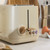 Stone-coloured 2-slice toaster with gold controls on kitchen counter