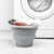 Grey collapsible laundry basket with towels, shown by washing machine