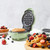 Green waffle maker with cooked waffle, surrounded by fresh berries and waffles.