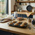 Tray of six blueberry muffins cooling on wooden kitchen counter with baking ingredients nearby