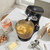 Black wood-effect stand mixer with metal bowl mixing cake batter on kitchen counter
