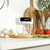 Manual food chopper on kitchen counter with garlic, basil and tomatoes displayed beside it