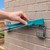 Hand fitting teal retractable washing line to grey brick wall mount