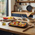 Tray of chopped vegetables ready to roast on wooden kitchen counter