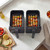 Two black air fryer baskets with chicken and vegetable skewers on a kitchen counter
