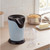 Blue and black electric popcorn maker on kitchen counter with lid and scoop