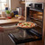 Freshly baked margherita pizza on tray being taken out of home oven in kitchen.