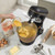 Black wood-effect stand mixer with whisk, mixing ingredients in kitchen setting