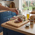 Sliced cooked beef joint on wooden board with hand sprinkling salt in kitchen setting