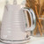 Pink ribbed electric kettle with chrome handle on kitchen countertop