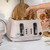 Pink four-slice toaster with bread being toasted, hand placing a slice.
