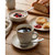 Breakfast set: ceramic mug of black coffee, bowl of porridge with berries, crumpets with jam.