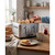 Silver four-slice toaster in kitchen with bread and breakfast foods on wooden table