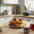 Stack of waffles with butter, syrup and berries on plate in modern kitchen