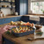 Oven tray with roasted root vegetables on wooden kitchen counter in country blue kitchen