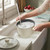 Cream ribbed saucepan being hand washed in kitchen sink, glass lid on counter