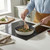 Cream ceramic frying pan cooking mushrooms and greens on induction hob