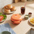 Orange mini burger maker on kitchen counter, next to buns, fries, salad and drink
