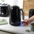 Black electric kettle being switched on in a modern kitchen setting