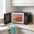 Black microwave with open door showing a bowl of soup on the turntable, in a modern kitchen.