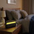 Black wireless speaker with yellow LED light on bedside table, bedroom setting