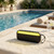 Black wireless speaker with yellow LED strip on poolside towel