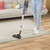 Corded stick vacuum cleaning beige rug on wood floor, shown in home setting