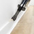 Vacuum cleaner crevice tool cleaning skirting board edge on light wood floor