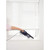 Handheld vacuum cleaning white window sill, shown in use with blinds in background