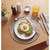 Avocado toast with fried egg, gold cutlery, orange juice on breakfast table.